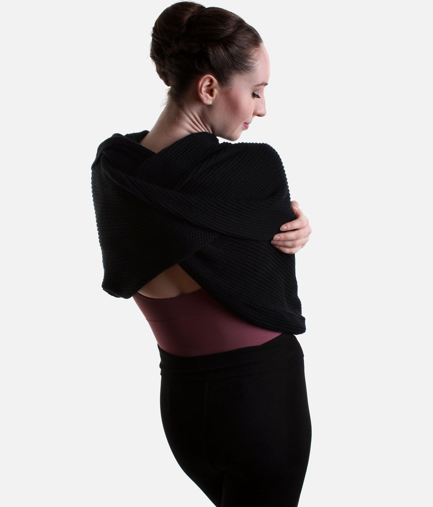 Black Mirella Adagio warm-up scarf worn as a cropped bolero, showing long sleeves and a twisted drape over a plum leotard.