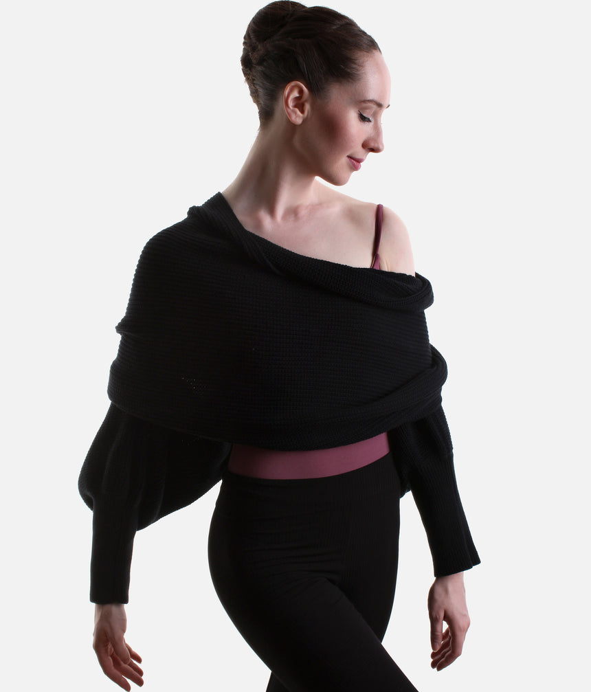 Black Mirella Adagio warm-up scarf worn as a cropped bolero, showing long sleeves and a twisted drape over a plum leotard.