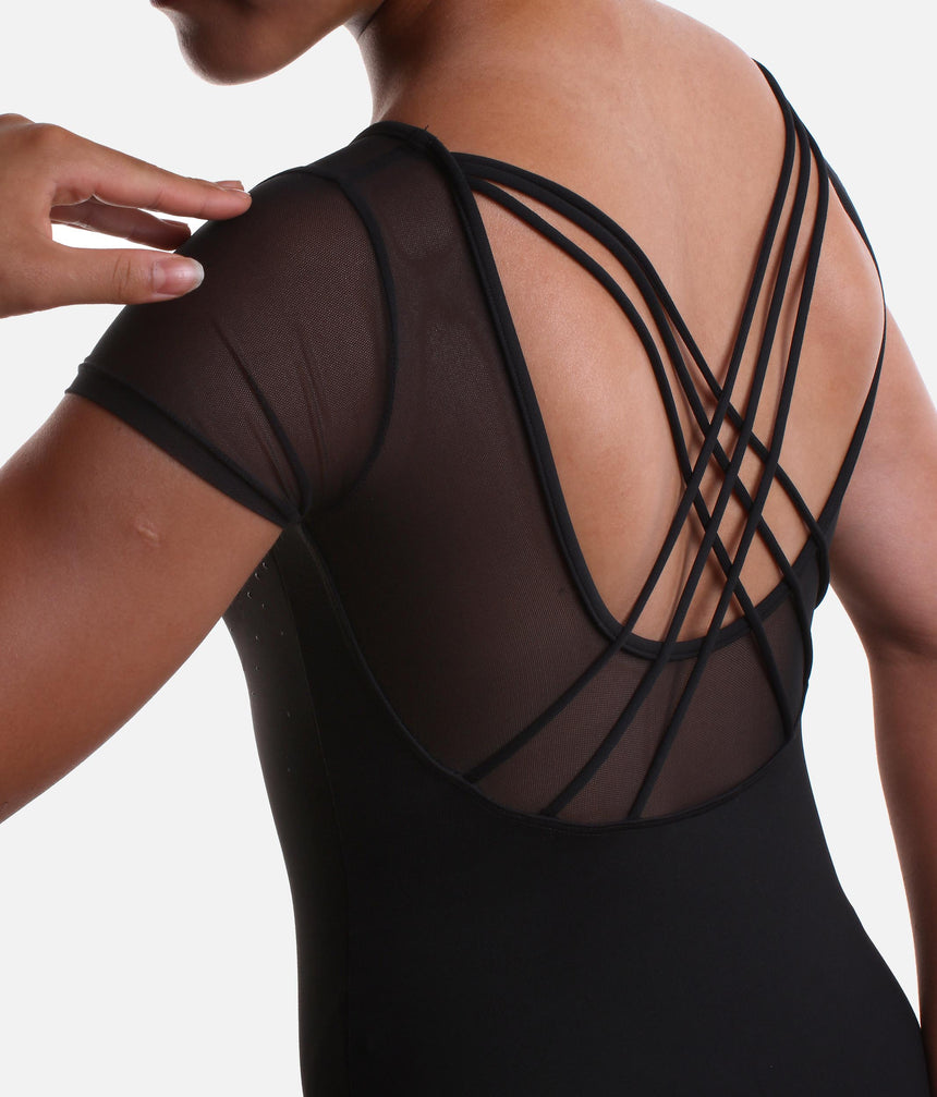 Close-up back view of a model wearing a black short-sleeve bodysuit or dance leotard with sheer mesh shoulder panels and multiple crisscross strappy details across the open back, against a light gray studio background.