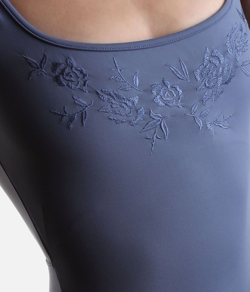 Detail of tonal flowers and leafy stems embroidered beneath the neckline of the blue Mirella Adagio ballet leotard.