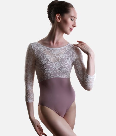 A woman modeling a three-quarter sleeve ballet leotard with a white floral lace bodice and a dusty mauve-pink solid skirt, set against a plain light gray background.