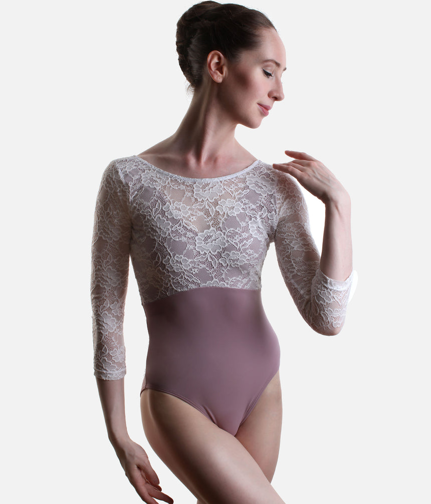 A woman modeling a three-quarter sleeve ballet leotard with a white floral lace bodice and a dusty mauve-pink solid skirt, set against a plain light gray background.