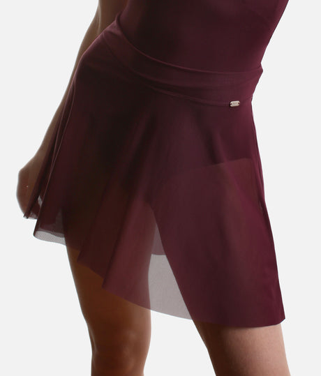 Angled front detail of the Mirella Adagio skirt in Merlot, with a broad waistband, small logo plaque and sheer mesh over the legs.