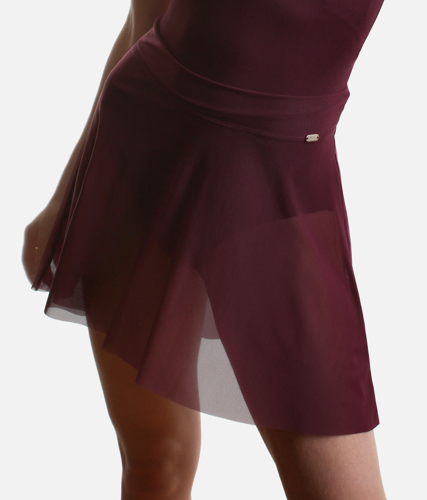 Angled front detail of the Mirella Adagio skirt in Merlot, with a broad waistband, small logo plaque and sheer mesh over the legs.